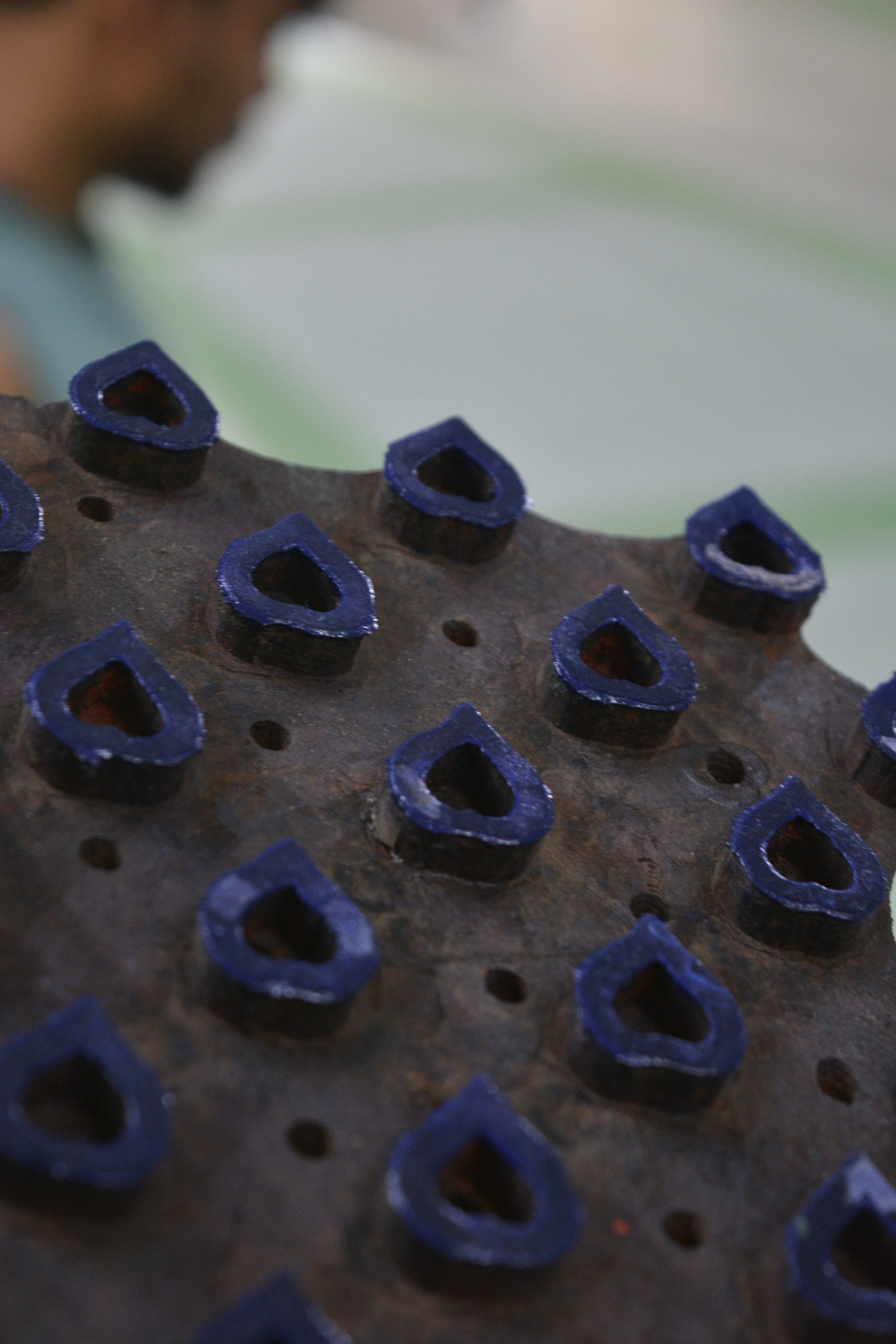 Close-up macro of a carved wooden printing block loaded with blue dye, carved teardrop motifs visible